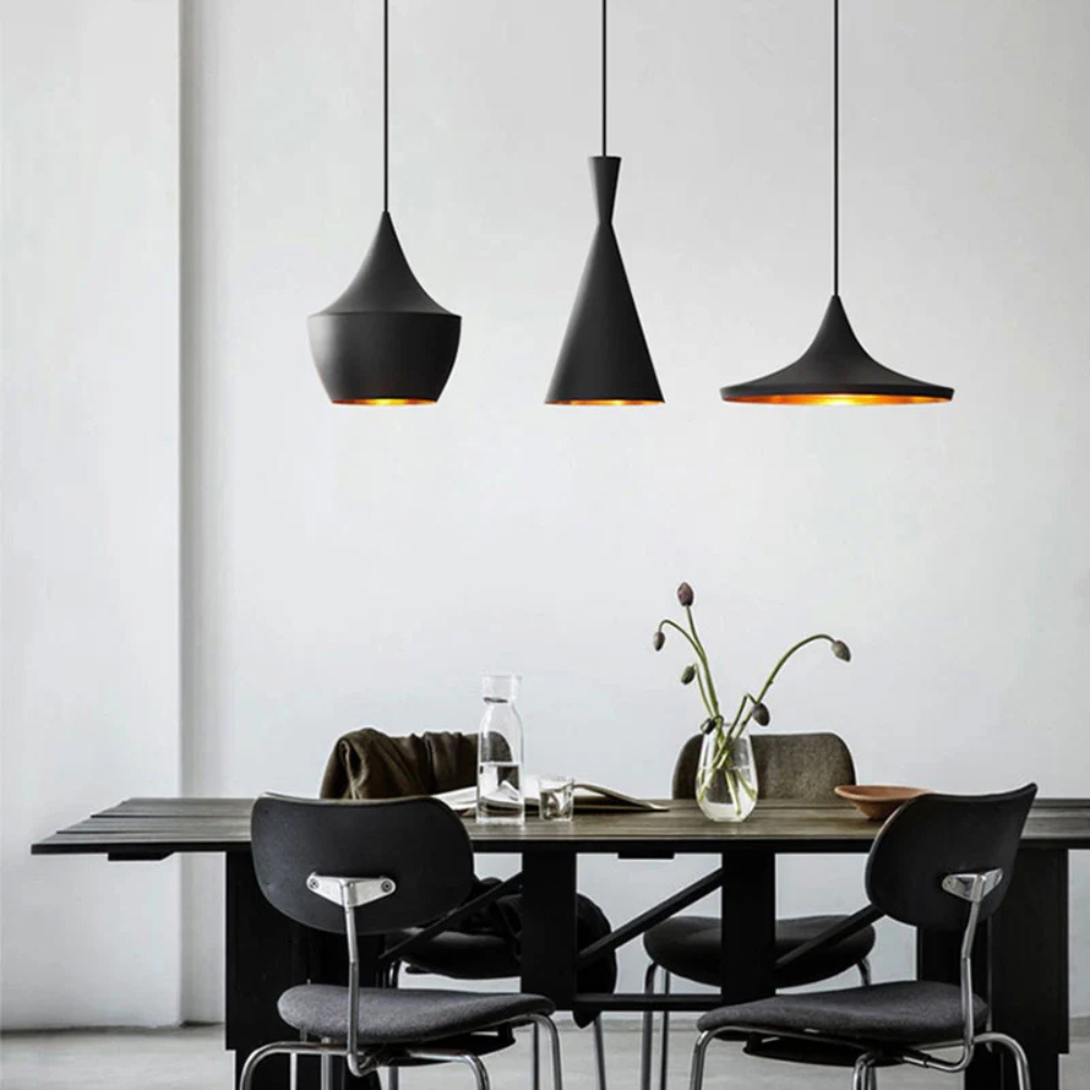 Vintage pendant lamps Style A, B, and C in black and gold suspended above a dining table in a stylish dining room.